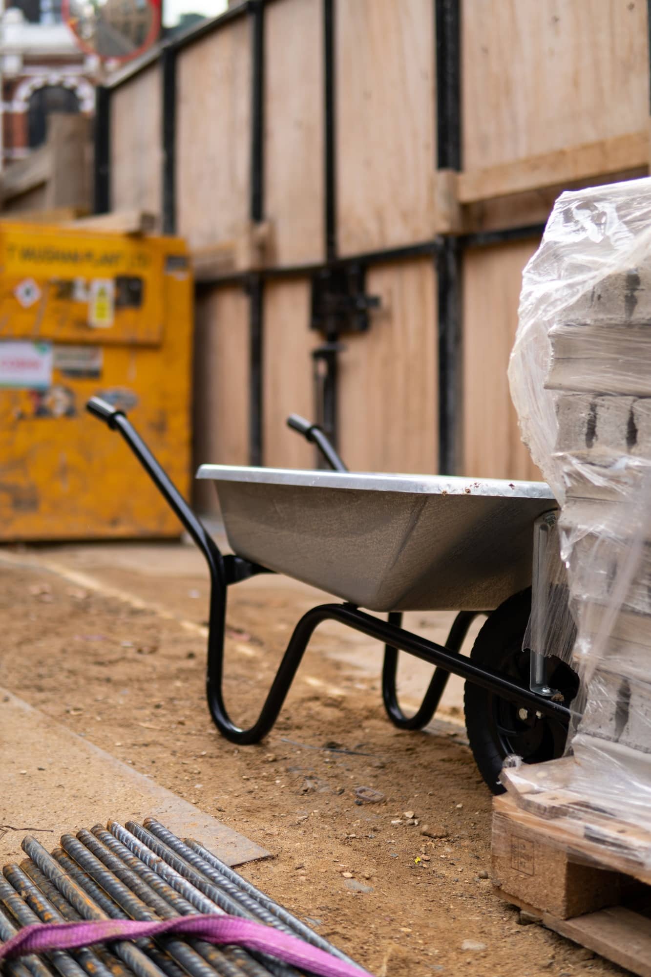 Wheel barrow on construction site with timber hoarding in background